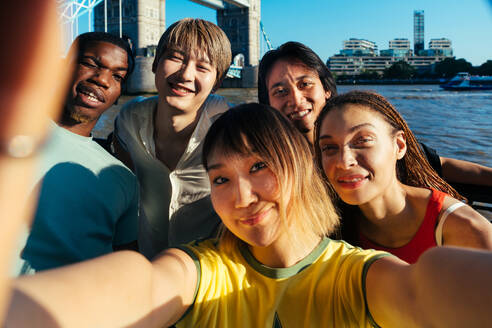 Multirassische Gruppe von glücklichen jungen Freunden in der Londoner City - Multiethnische Teenager treffen sich und haben Spaß in der Tower Bridge, UK - Konzepte über jugendlichen Lebensstil, Reisen und Tourismus - DMDF08688