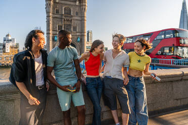 Multirassische Gruppe von glücklichen jungen Freunden in der Londoner City - Multiethnische Teenager treffen sich und haben Spaß in der Tower Bridge, UK - Konzepte über jugendlichen Lebensstil, Reisen und Tourismus - DMDF08711