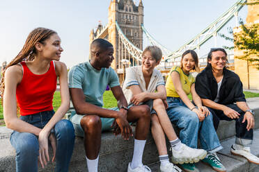 Multirassische Gruppe von glücklichen jungen Freunden in der Londoner City - Multiethnische Teenager treffen sich und haben Spaß in der Tower Bridge, UK - Konzepte über jugendlichen Lebensstil, Reisen und Tourismus - DMDF08729