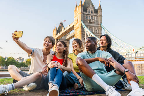 Multirassische Gruppe von glücklichen jungen Freunden in der Londoner City - Multiethnische Teenager treffen sich und haben Spaß in der Tower Bridge, UK - Konzepte über jugendlichen Lebensstil, Reisen und Tourismus - DMDF08736