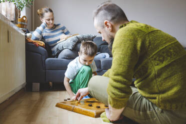 Father playing checkers with son on floor at home - IHF01862