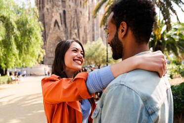 Multiracial beautiful happy couple of lovers dating at Sagrada Familia, Barcelona - Multiethnic tourists travelling in Europe and visiting a city in Spain, concepts about tourism and people lifestyle - DMDF08745