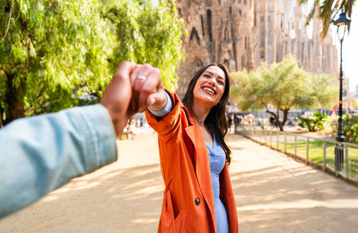 Multiracial beautiful happy couple of lovers dating at Sagrada Familia, Barcelona - Multiethnic tourists travelling in Europe and visiting a city in Spain, concepts about tourism and people lifestyle - DMDF08753