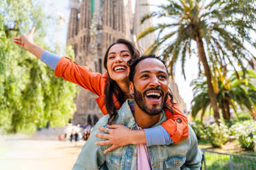 Multiracial beautiful happy couple of lovers dating at Sagrada Familia, Barcelona - Multiethnic tourists travelling in Europe and visiting a city in Spain, concepts about tourism and people lifestyle - DMDF08758
