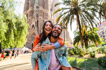 Multiracial beautiful happy couple of lovers dating at Sagrada Familia, Barcelona - Multiethnic tourists travelling in Europe and visiting a city in Spain, concepts about tourism and people lifestyle - DMDF08759