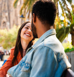 Multiracial beautiful happy couple of lovers dating at Sagrada Familia, Barcelona - Multiethnic tourists travelling in Europe and visiting a city in Spain, concepts about tourism and people lifestyle - DMDF08762