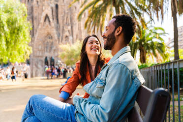 Multiracial beautiful happy couple of lovers dating at Sagrada Familia, Barcelona - Multiethnic tourists travelling in Europe and visiting a city in Spain, concepts about tourism and people lifestyle - DMDF08764