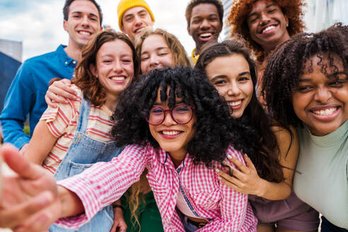 Happy playful multiethnic group of young friends bonding outdoors - Multiracial millennials students meeting in the city, concepts of youth, people lifestyle, diversity, teenage and urban life - DMDF08832