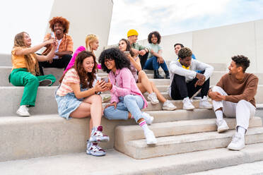 Happy playful multiethnic group of young friends bonding outdoors - Multiracial millennials students meeting in the city, concepts of youth, people lifestyle, diversity, teenage and urban life - DMDF08842