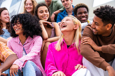 Happy playful multiethnic group of young friends bonding outdoors - Multiracial millennials students meeting in the city, concepts of youth, people lifestyle, diversity, teenage and urban life - DMDF08855