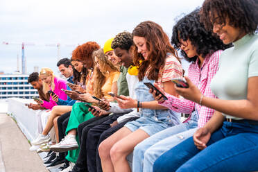 Happy playful multiethnic group of young friends bonding outdoors - Multiracial millennials students meeting in the city, concepts of youth, people lifestyle, diversity, teenage and urban life - DMDF08892