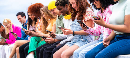 Happy playful multiethnic group of young friends bonding outdoors - Multiracial millennials students meeting in the city, concepts of youth, people lifestyle, diversity, teenage and urban life - DMDF08894