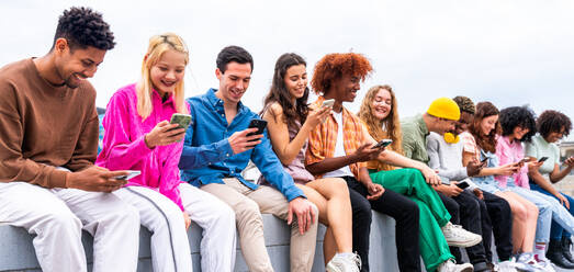 Happy playful multiethnic group of young friends bonding outdoors - Multiracial millennials students meeting in the city, concepts of youth, people lifestyle, diversity, teenage and urban life - DMDF08900