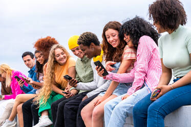 Happy playful multiethnic group of young friends bonding outdoors - Multiracial millennials students meeting in the city, concepts of youth, people lifestyle, diversity, teenage and urban life - DMDF08904