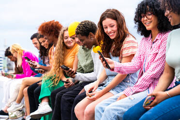 Happy playful multiethnic group of young friends bonding outdoors - Multiracial millennials students meeting in the city, concepts of youth, people lifestyle, diversity, teenage and urban life - DMDF08905