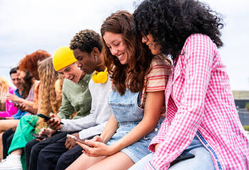 Happy playful multiethnic group of young friends bonding outdoors - Multiracial millennials students meeting in the city, concepts of youth, people lifestyle, diversity, teenage and urban life - DMDF08907