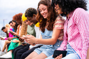 Happy playful multiethnic group of young friends bonding outdoors - Multiracial millennials students meeting in the city, concepts of youth, people lifestyle, diversity, teenage and urban life - DMDF08910