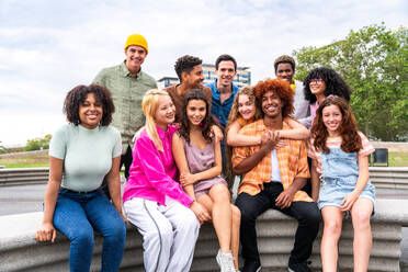 Fröhliche, verspielte, multiethnische Gruppe junger Freunde, die sich im Freien treffen - Multirassische Millennial-Studenten, die sich in der Stadt treffen, Konzepte von Jugend, Lebensstil, Vielfalt, Teenager- und Stadtleben - DMDF08936
