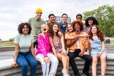 Fröhliche, verspielte, multiethnische Gruppe junger Freunde, die sich im Freien treffen - Multirassische Millennial-Studenten, die sich in der Stadt treffen, Konzepte von Jugend, Lebensstil, Vielfalt, Teenager- und Stadtleben - DMDF08937