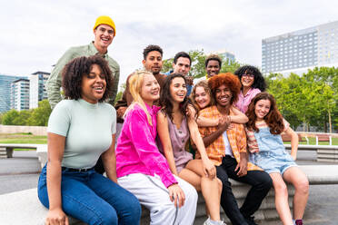 Fröhliche, verspielte, multiethnische Gruppe junger Freunde, die sich im Freien treffen - Multirassische Millennial-Studenten, die sich in der Stadt treffen, Konzepte von Jugend, Lebensstil, Vielfalt, Teenager- und Stadtleben - DMDF08938