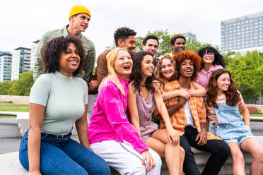 Fröhliche, verspielte, multiethnische Gruppe junger Freunde, die sich im Freien treffen - Multirassische Millennial-Studenten, die sich in der Stadt treffen, Konzepte von Jugend, Lebensstil, Vielfalt, Teenager- und Stadtleben - DMDF08939