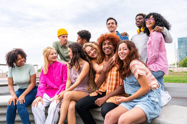 Fröhliche, verspielte, multiethnische Gruppe junger Freunde, die sich im Freien treffen - Multirassische Millennial-Studenten, die sich in der Stadt treffen, Konzepte von Jugend, Lebensstil, Vielfalt, Teenager- und Stadtleben - DMDF08947