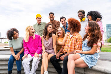 Fröhliche, verspielte, multiethnische Gruppe junger Freunde, die sich im Freien treffen - Multirassische Millennial-Studenten, die sich in der Stadt treffen, Konzepte von Jugend, Lebensstil, Vielfalt, Teenager- und Stadtleben - DMDF08949