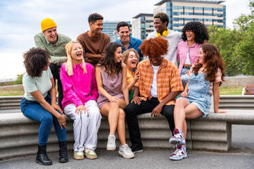 Fröhliche, verspielte, multiethnische Gruppe junger Freunde, die sich im Freien treffen - Multirassische Millennial-Studenten, die sich in der Stadt treffen, Konzepte von Jugend, Lebensstil, Vielfalt, Teenager- und Stadtleben - DMDF08954