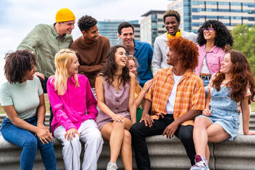 Fröhliche, verspielte, multiethnische Gruppe junger Freunde, die sich im Freien treffen - Multirassische Millennial-Studenten, die sich in der Stadt treffen, Konzepte von Jugend, Lebensstil, Vielfalt, Teenager- und Stadtleben - DMDF08955