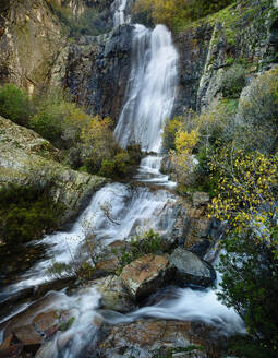 The Despeñalagua Waterfall cascades serenely through the rocky terrain surrounded by autumn foliage in Valverde de los Arroyos, Guadalajara. - ADSF50943