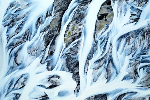 Aerial view of intricate river basins in Iceland, showcasing the beautiful patterns created by flowing water amidst snow - ADSF51053