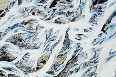 An aerial snapshot capturing the intricate patterns of river basins amidst the contrasting landscape of Iceland - ADSF51070