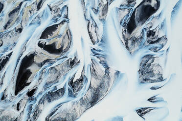 Aerial view of a frozen river basin in Iceland, showcasing the intricate patterns of ice and snow from above - ADSF51083