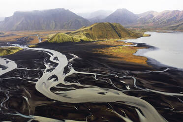 An aerial shot captures the natural beauty of Iceland's river basins, with winding rivers slicing through the landscape against a backdrop of mountains - ADSF51090