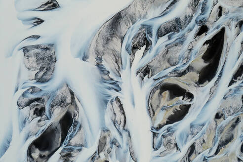 Captivating aerial of frozen river basins in Iceland, showcasing nature's art with patterns etched in ice and snow - ADSF51096