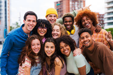 Happy playful multiethnic group of young friends bonding outdoors - Multiracial millennials students meeting in the city, concepts of youth, people lifestyle, diversity, teenage and urban life - DMDF08981