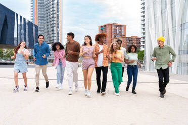 Happy playful multiethnic group of young friends bonding outdoors - Multiracial millennials students meeting in the city, concepts of youth, people lifestyle, diversity, teenage and urban life - DMDF08984