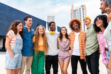 Happy playful multiethnic group of young friends bonding outdoors - Multiracial millennials students meeting in the city, concepts of youth, people lifestyle, diversity, teenage and urban life - DMDF09014