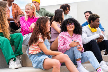 Happy playful multiethnic group of young friends bonding outdoors - Multiracial millennials students meeting in the city, concepts of youth, people lifestyle, diversity, teenage and urban life - DMDF09031