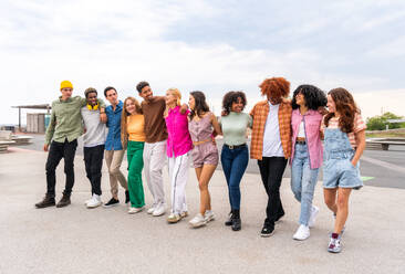 Happy playful multiethnic group of young friends bonding outdoors - Multiracial millennials students meeting in the city, concepts of youth, people lifestyle, diversity, teenage and urban life - DMDF09049