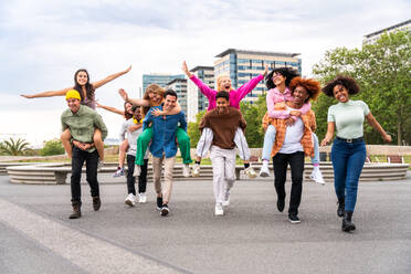 Happy playful multiethnic group of young friends bonding outdoors - Multiracial millennials students meeting in the city, concepts of youth, people lifestyle, diversity, teenage and urban life - DMDF09052