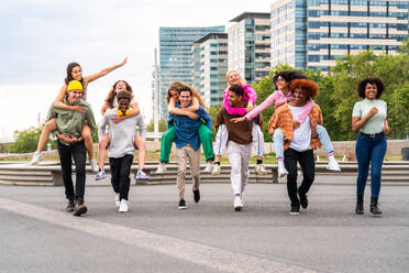 Happy playful multiethnic group of young friends bonding outdoors - Multiracial millennials students meeting in the city, concepts of youth, people lifestyle, diversity, teenage and urban life - DMDF09056