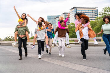 Happy playful multiethnic group of young friends bonding outdoors - Multiracial millennials students meeting in the city, concepts of youth, people lifestyle, diversity, teenage and urban life - DMDF09066