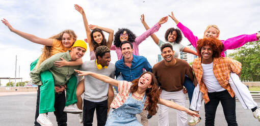 Happy playful multiethnic group of young friends bonding outdoors - Multiracial millennials students meeting in the city, concepts of youth, people lifestyle, diversity, teenage and urban life - DMDF09072