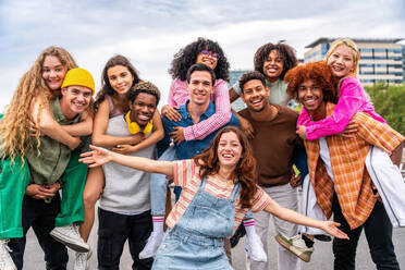 Happy playful multiethnic group of young friends bonding outdoors - Multiracial millennials students meeting in the city, concepts of youth, people lifestyle, diversity, teenage and urban life - DMDF09075