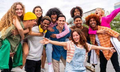 Happy playful multiethnic group of young friends bonding outdoors - Multiracial millennials students meeting in the city, concepts of youth, people lifestyle, diversity, teenage and urban life - DMDF09080