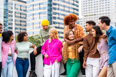 Happy playful multiethnic group of young friends bonding outdoors - Multiracial millennials students meeting in the city, concepts of youth, people lifestyle, diversity, teenage and urban life - DMDF09118