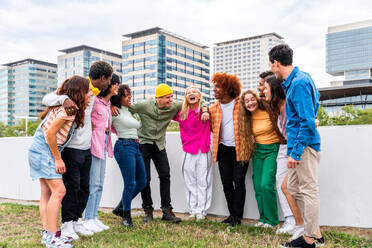 Happy playful multiethnic group of young friends bonding outdoors - Multiracial millennials students meeting in the city, concepts of youth, people lifestyle, diversity, teenage and urban life - DMDF09133