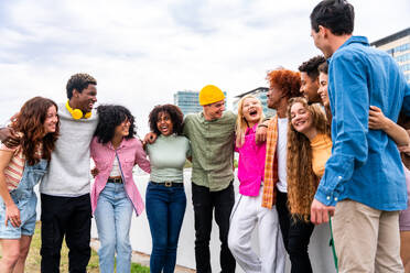 Happy playful multiethnic group of young friends bonding outdoors - Multiracial millennials students meeting in the city, concepts of youth, people lifestyle, diversity, teenage and urban life - DMDF09137