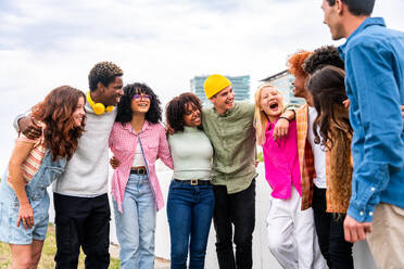 Happy playful multiethnic group of young friends bonding outdoors - Multiracial millennials students meeting in the city, concepts of youth, people lifestyle, diversity, teenage and urban life - DMDF09139